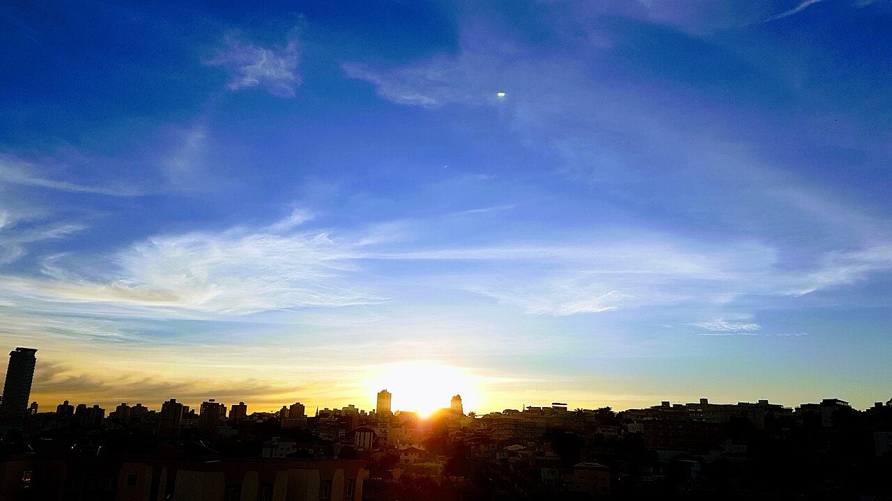 Pôr do sol sobre o bairro Santa Tereza, com a torre da igreja ao fundo, em Belo Horizonte